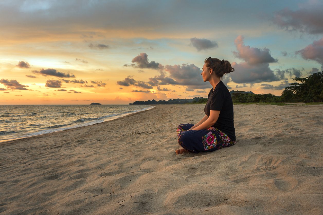 Woman relaxing on beach at sunset